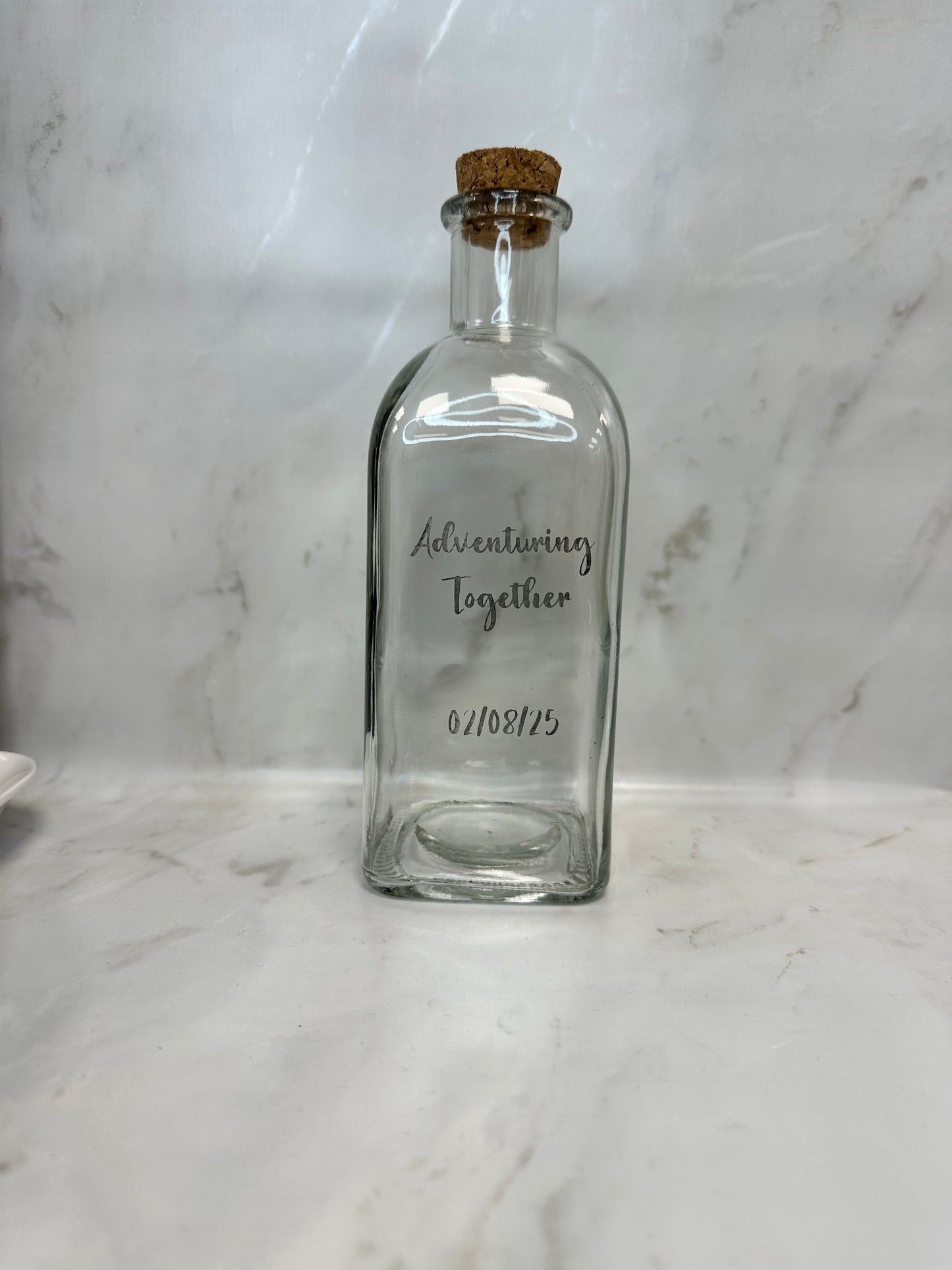 Clear glass bottle with cork on a marble surface