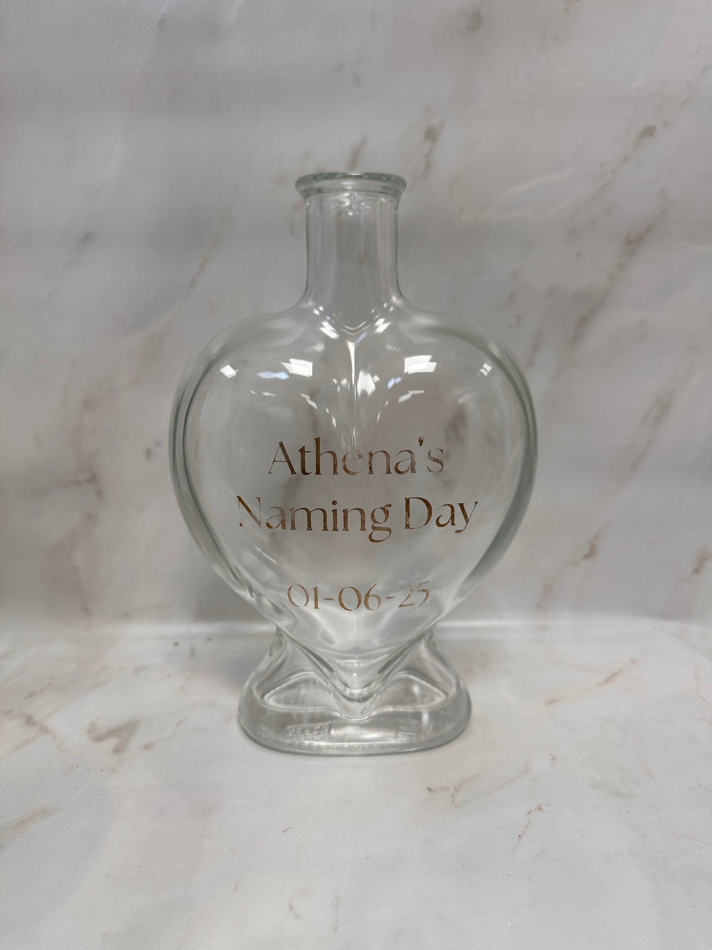 Clear glass bottle with engraved text on a marble surface