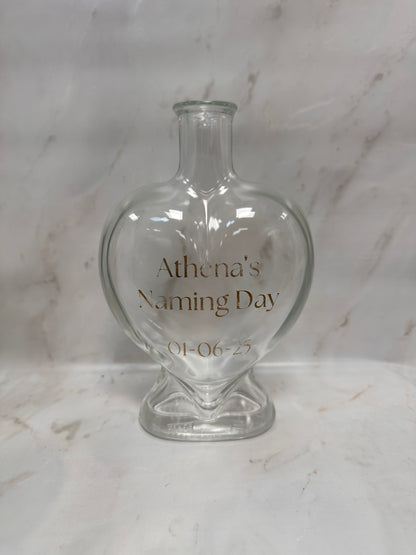 Clear glass bottle with engraved text on a marble surface