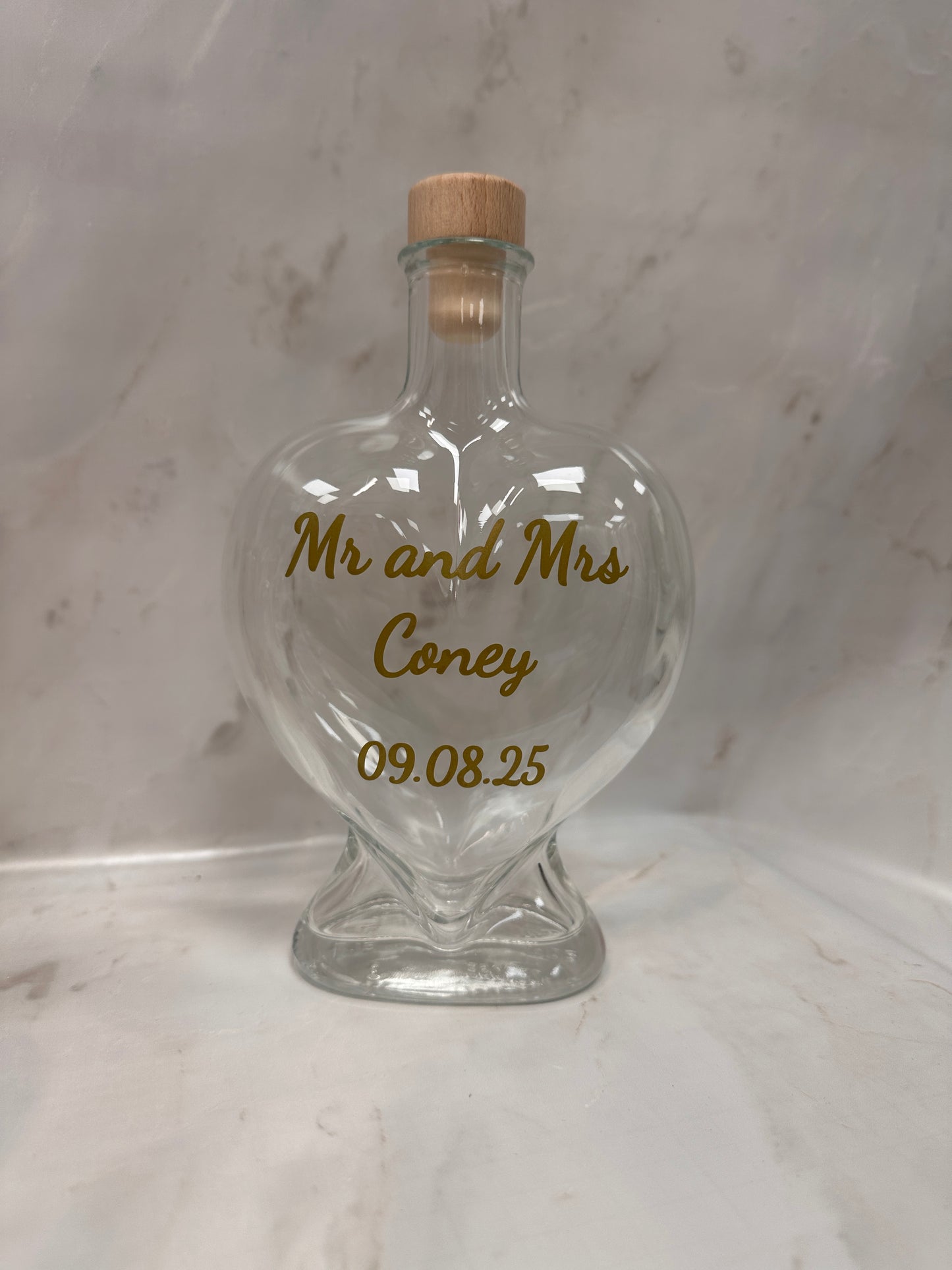 Decorative glass bottle with engraved text on a marble surface